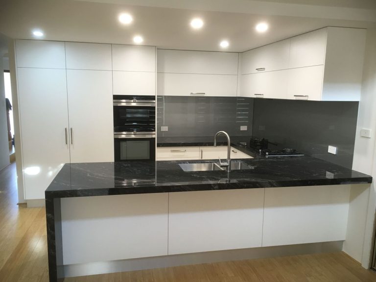 Modern white kitchen with black stone island bench