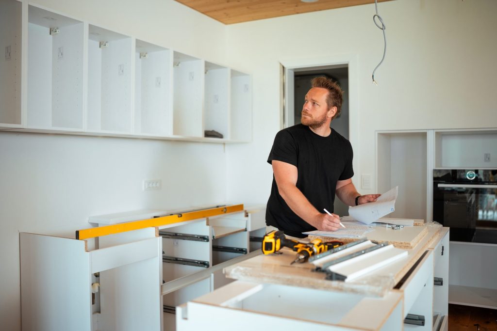 Man installing kitchen cabinets checking plans indoors