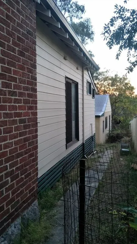 Side of brick and weatherboard house with fence