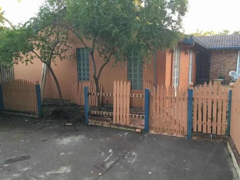 Peach house with picket fence, trees and driveway