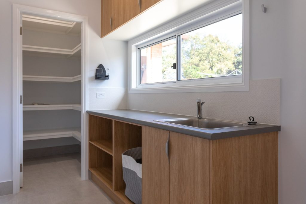 Modern laundry with timber cabinets, sink and window