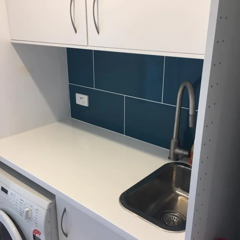 Compact laundry with sink, washing machine and blue tiles
