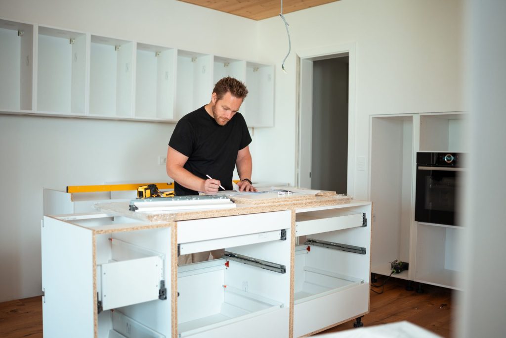 Man measuring kitchen cabinets during renovation